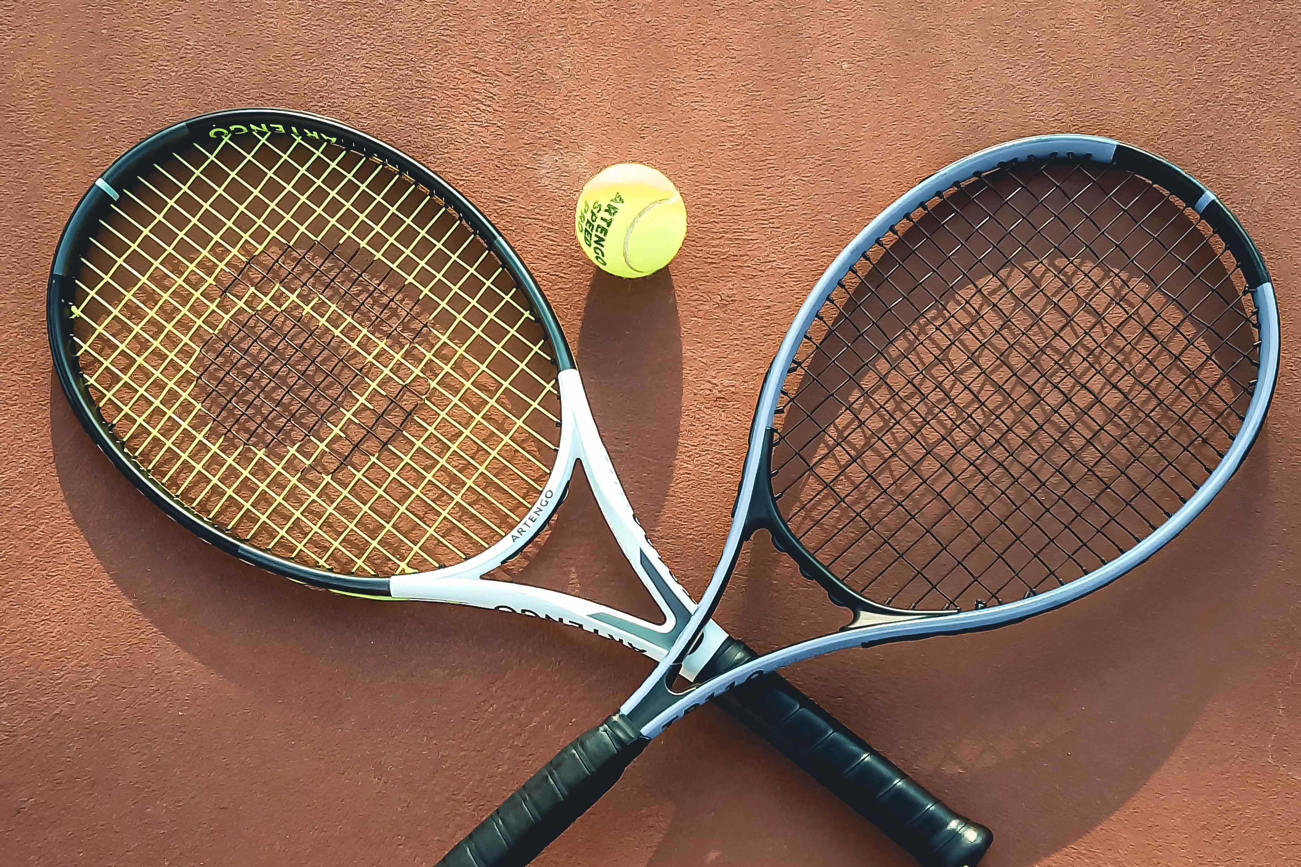 Two crossed rackets and a ball lying on a clay court