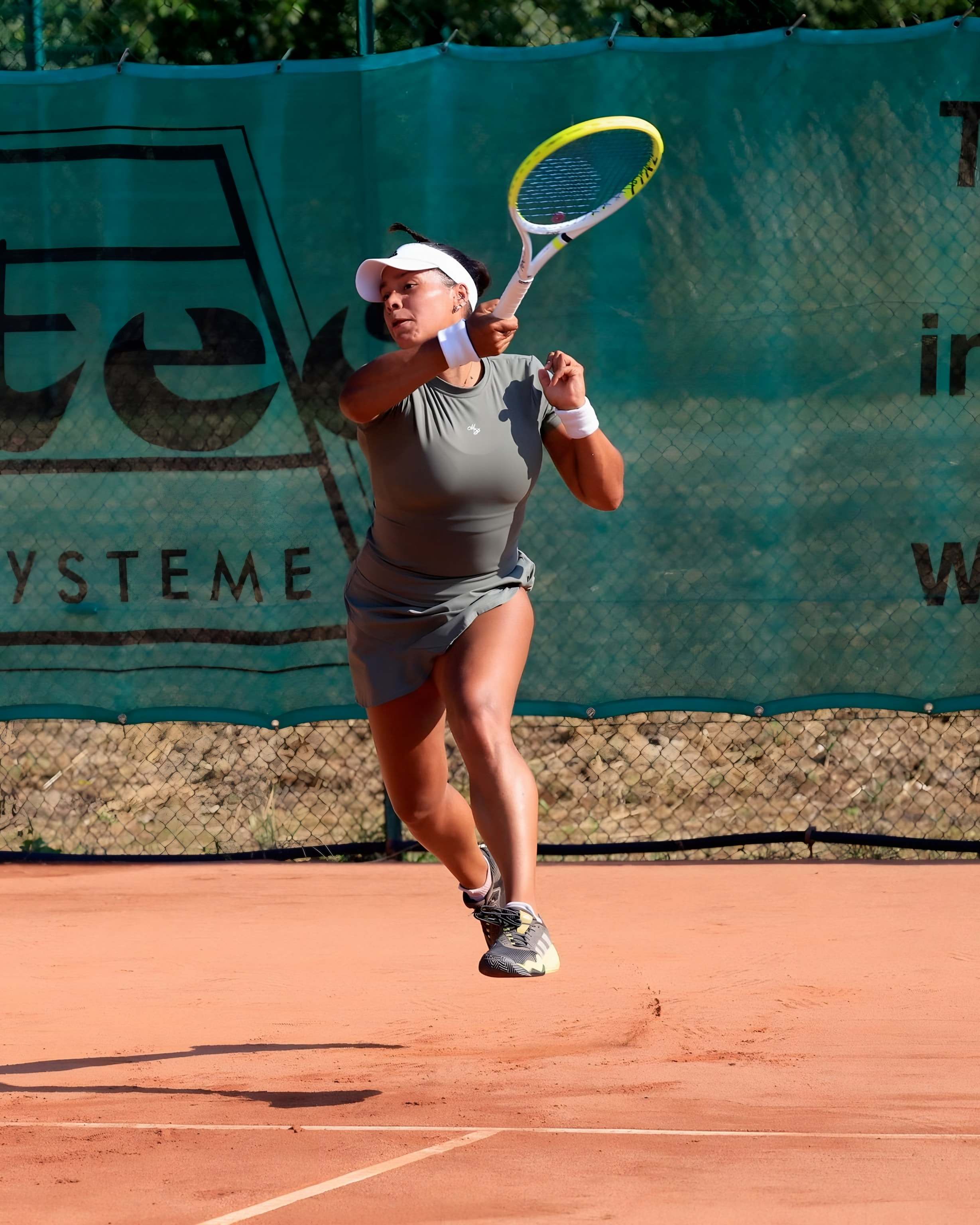 Jade hitting a leaping forehand on a clay court